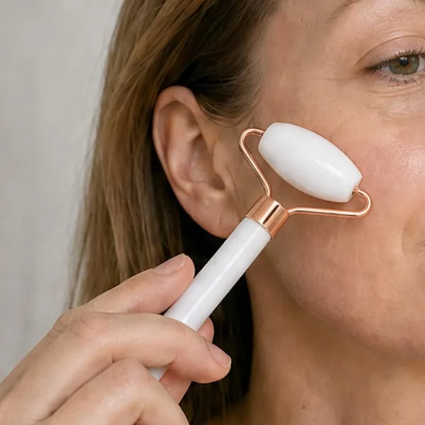 A woman gliding the white stone facial roller over her cheek