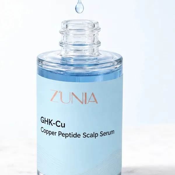 A drop of light-blue serum falling into the ZÚNIA scalp serum bottle