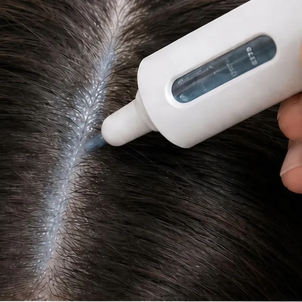 The precision applicator placing serum along a hair part on dark hair